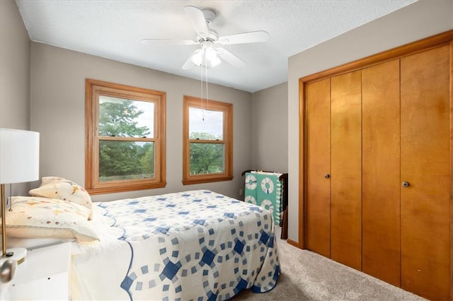 bedroom featuring a closet, a textured ceiling, carpet flooring, and ceiling fan