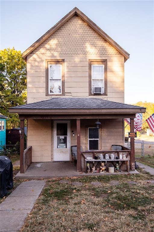 929 N 7th St, Atchison, KS 66002 - view of front of home featuring a porch, a shingled roof, and fence