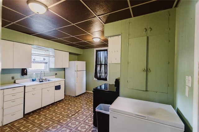 929 N 7th St, Atchison, KS 66002 - kitchen featuring freestanding refrigerator, a sink, light countertops, fridge, and white cabinets