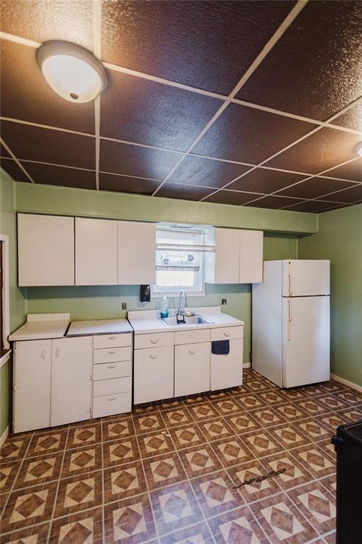 929 N 7th St, Atchison, KS 66002 - kitchen featuring freestanding refrigerator, a sink, light countertops, white cabinets, and dark floors