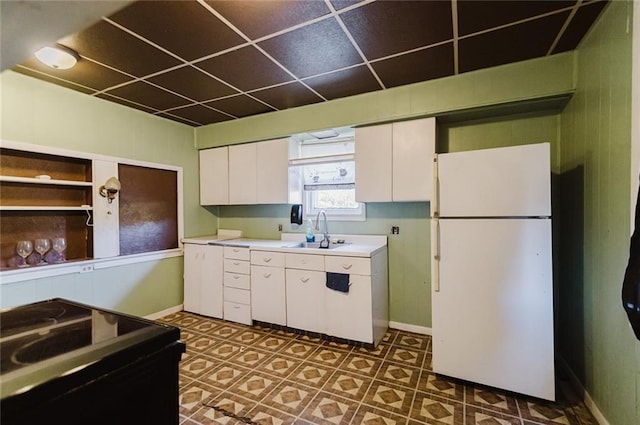 929 N 7th St, Atchison, KS 66002 - kitchen with freestanding refrigerator, a sink, black range with electric stovetop, white cabinetry, and light countertops