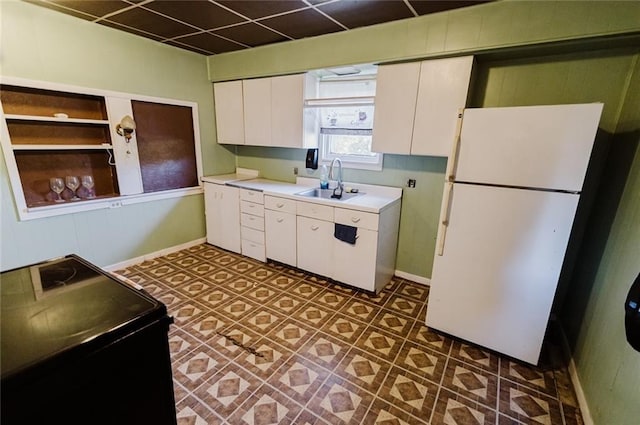 929 N 7th St, Atchison, KS 66002 - kitchen with freestanding refrigerator, a sink, white cabinets, light countertops, and baseboards