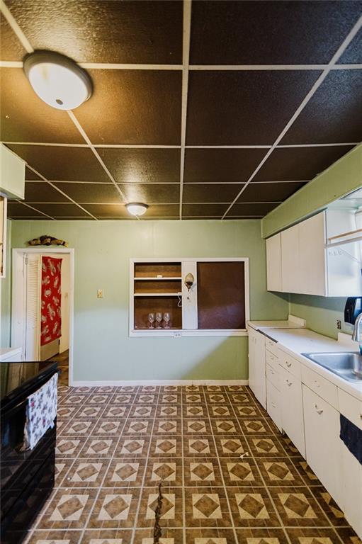 929 N 7th St, Atchison, KS 66002 - kitchen with a sink, white cabinets, light countertops, dishwasher, and a paneled ceiling