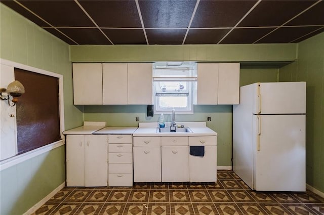 929 N 7th St, Atchison, KS 66002 - kitchen with freestanding refrigerator, a sink, light countertops, white cabinets, and a drop ceiling