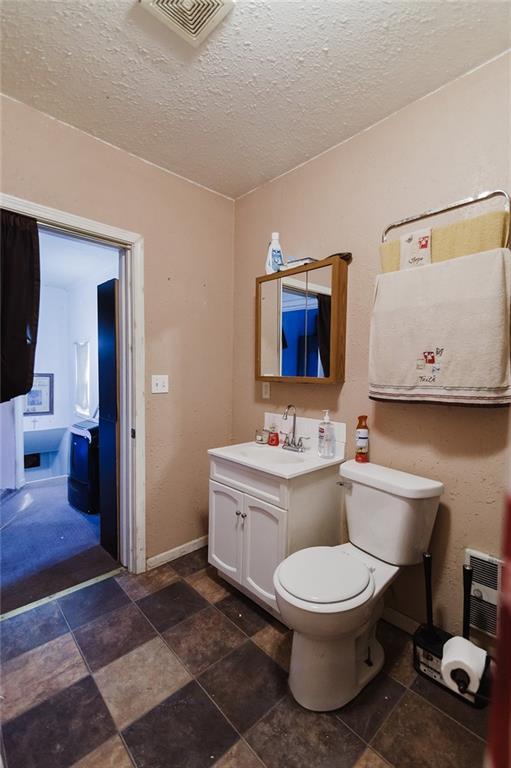 929 N 7th St, Atchison, KS 66002 - half bath featuring vanity, a textured ceiling, stone finish floors, toilet, and baseboards