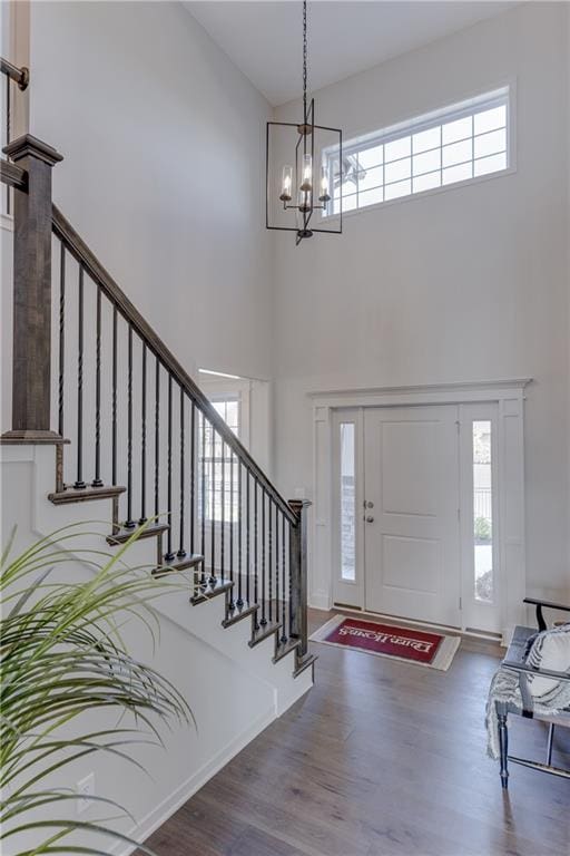 foyer featuring a notable chandelier, a healthy amount of sunlight, hardwood / wood-style floors, and a high ceiling