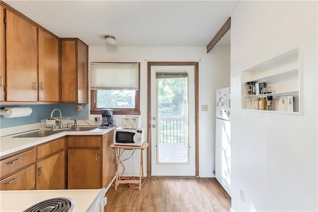 kitchen with beam ceiling, sink, and light hardwood / wood-style flooring