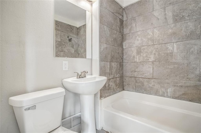 bathroom with toilet and tiled shower / bath