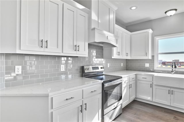 kitchen with stainless steel range with electric stovetop, white cabinetry, light stone countertops, and decorative backsplash