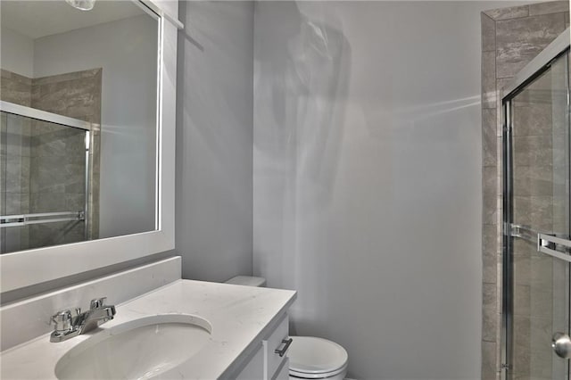 bathroom with a shower with door, vanity, and toilet