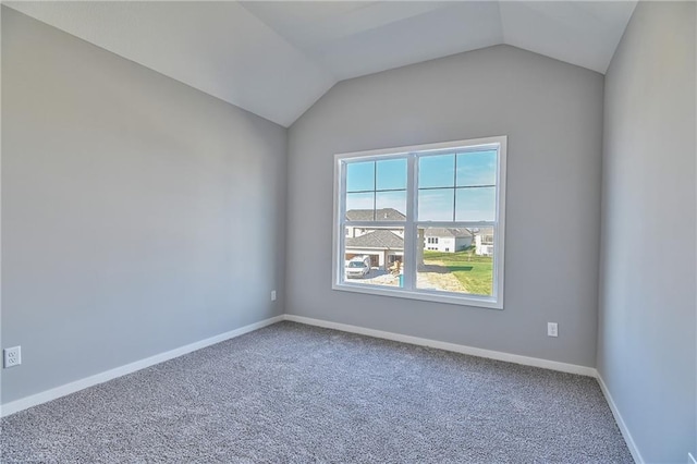 carpeted spare room featuring vaulted ceiling