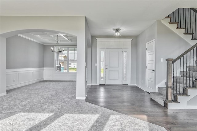 entrance foyer featuring beam ceiling, coffered ceiling, a notable chandelier, and dark hardwood / wood-style flooring