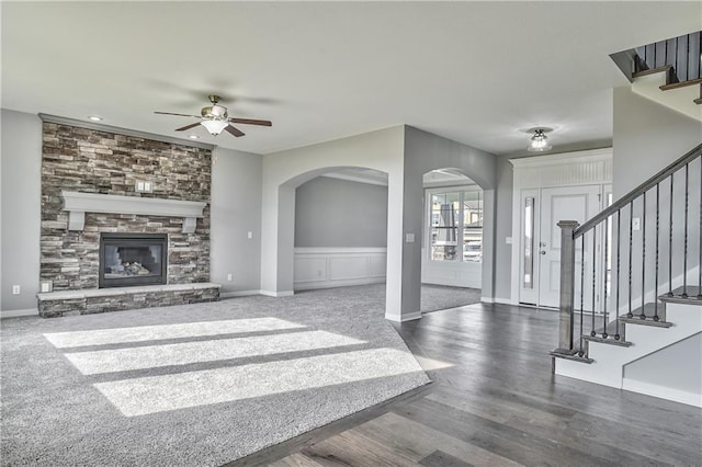 living room with dark hardwood / wood-style flooring, a stone fireplace, and ceiling fan