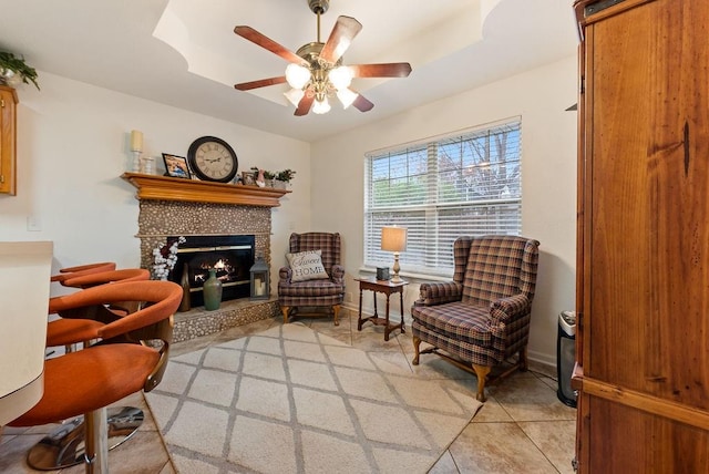 sitting room featuring a fireplace, ceiling fan, and light tile patterned flooring