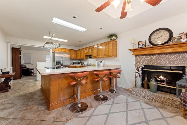 kitchen with ceiling fan, stainless steel appliances, a kitchen breakfast bar, kitchen peninsula, and a fireplace