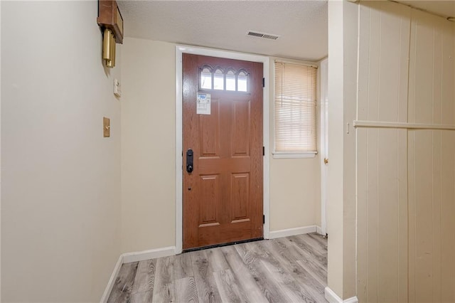 foyer entrance featuring a textured ceiling and light hardwood / wood-style floors