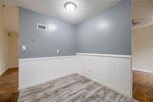 empty room featuring a textured ceiling, light hardwood / wood-style flooring, and ceiling fan