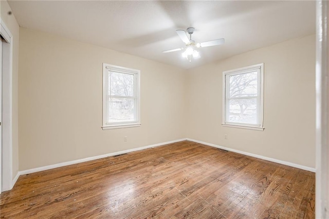 empty room with hardwood / wood-style floors, ceiling fan, and a healthy amount of sunlight