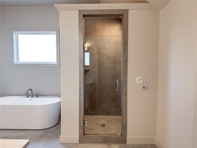 full bathroom with a stall shower, a soaking tub, baseboards, and tile patterned floors