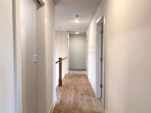 hallway featuring light wood finished floors, an upstairs landing, and baseboards