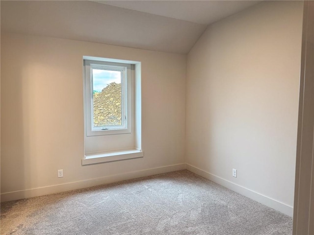 carpeted empty room featuring baseboards and lofted ceiling