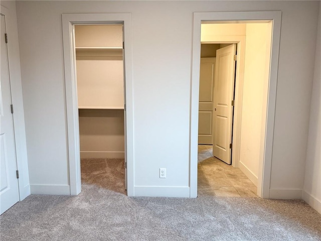 unfurnished bedroom featuring carpet flooring, a closet, and a walk in closet