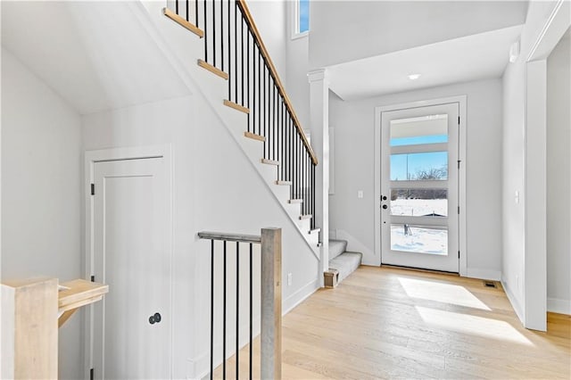 foyer featuring light wood-type flooring, stairway, and baseboards