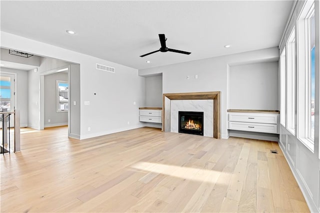 unfurnished living room featuring ceiling fan, light wood-style floors, a fireplace, baseboards, and recessed lighting