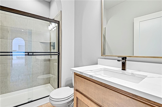 bathroom with toilet, a stall shower, and vanity