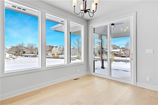 unfurnished room with wood finished floors, baseboards, and a chandelier