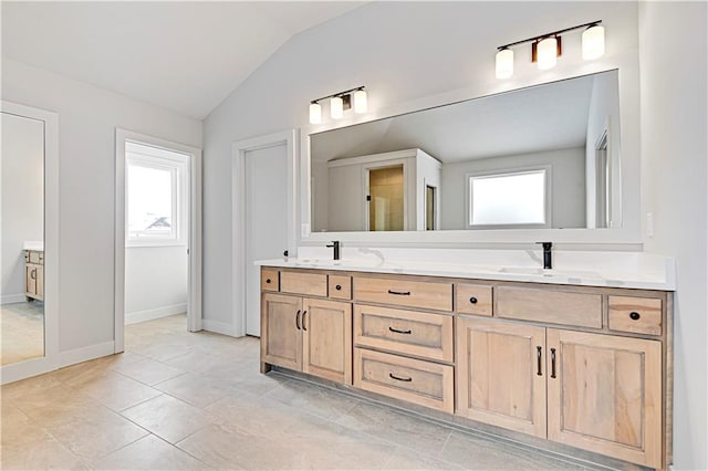 full bath featuring lofted ceiling, double vanity, and baseboards