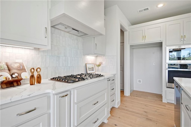 22070 W 100th Ter, Lenexa, KS 66220 - kitchen featuring appliances with stainless steel finishes, custom exhaust hood, light stone counters, white cabinets, and recessed lighting