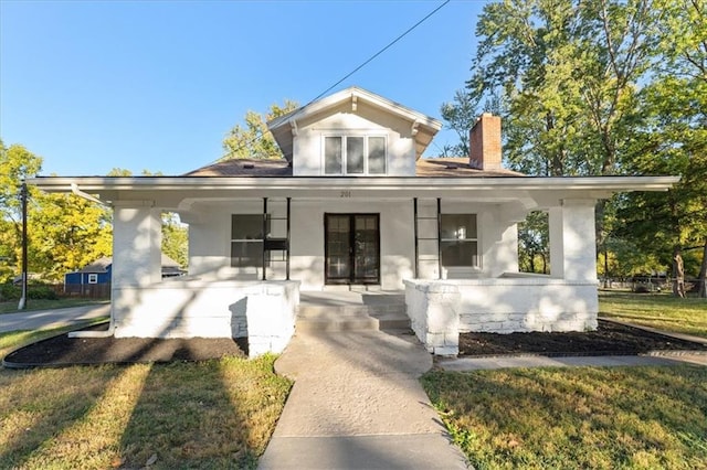 rear view of property featuring a yard and a porch