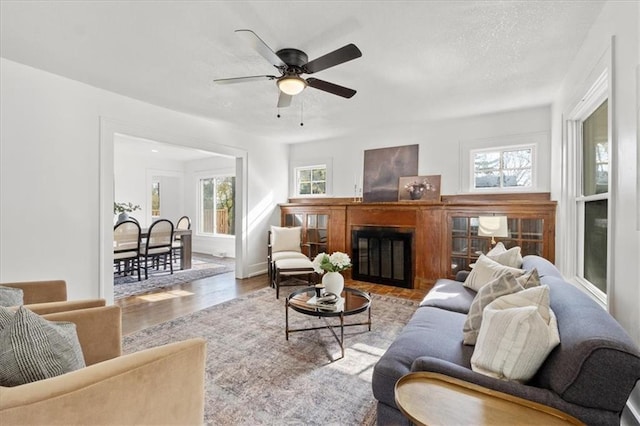 living room featuring ceiling fan, a wealth of natural light, and light wood-type flooring