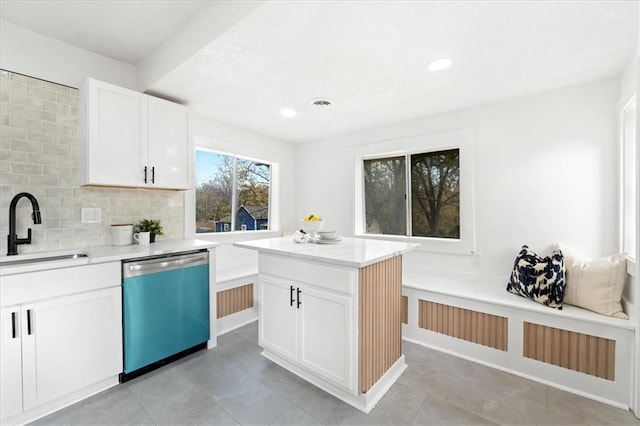 kitchen with white cabinets, stainless steel dishwasher, sink, and a kitchen island