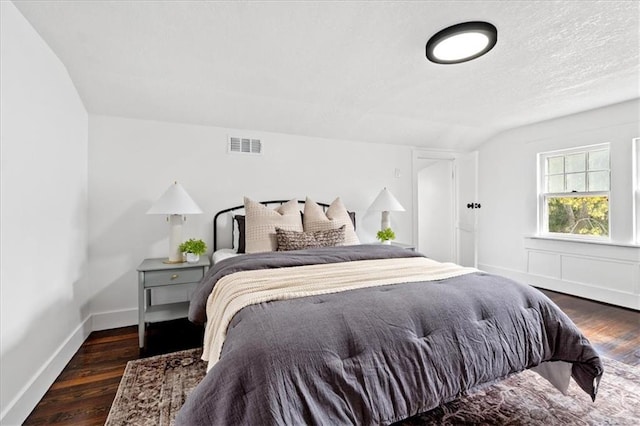 bedroom with vaulted ceiling and dark hardwood / wood-style flooring