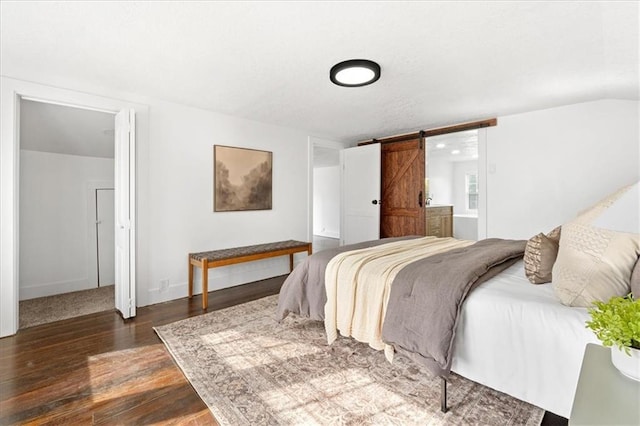 bedroom with a barn door and dark hardwood / wood-style flooring