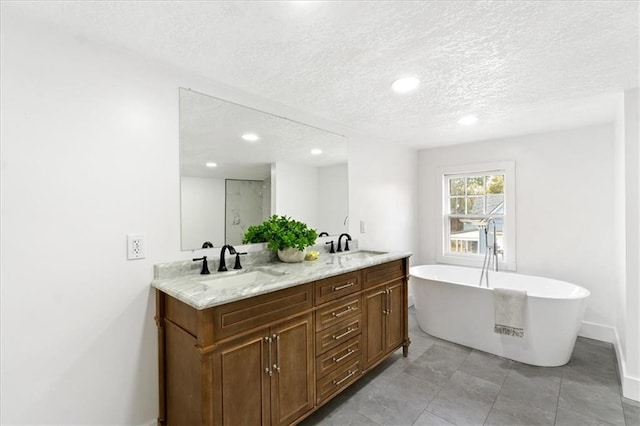 bathroom with vanity, a textured ceiling, a bath, and tile patterned floors