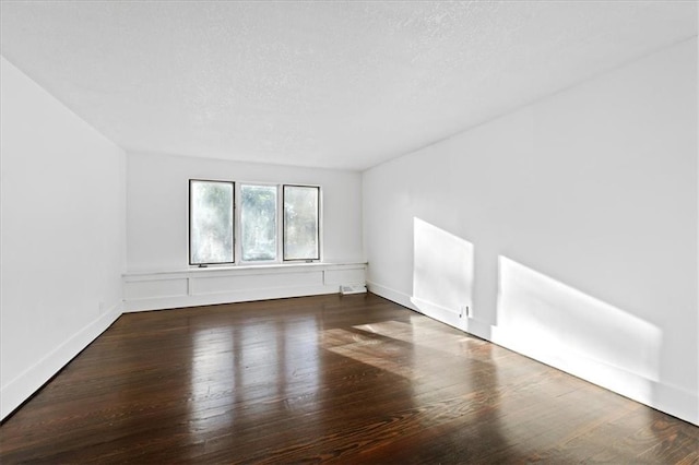 unfurnished room with dark wood-type flooring and a textured ceiling