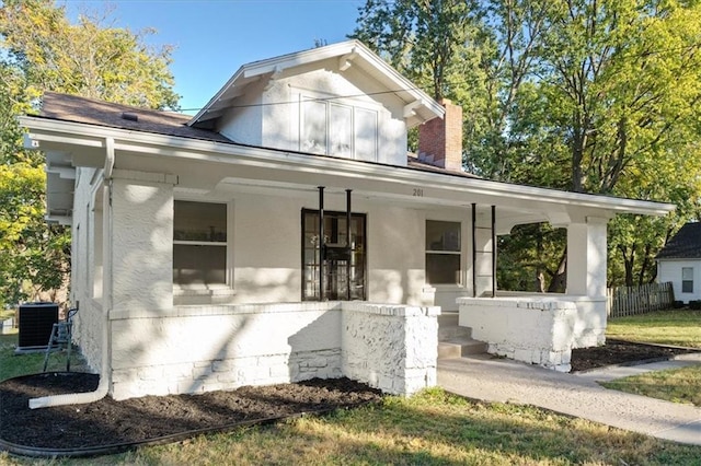 view of front facade featuring a porch, a front yard, and central AC