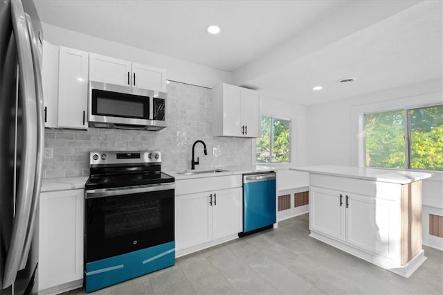 kitchen with a healthy amount of sunlight, appliances with stainless steel finishes, sink, and white cabinets