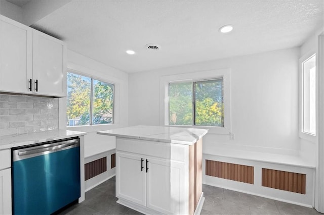 kitchen with tasteful backsplash, light stone countertops, dishwasher, tile patterned floors, and white cabinets