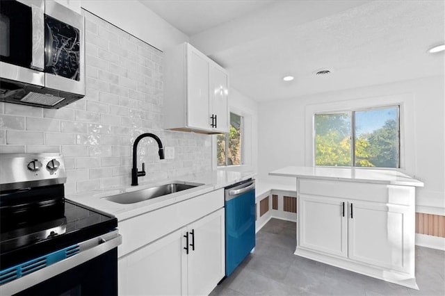 kitchen with sink, light tile patterned flooring, backsplash, stainless steel appliances, and white cabinets