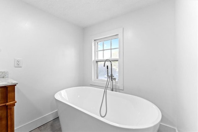 bathroom featuring vanity, tile patterned floors, a textured ceiling, and a washtub