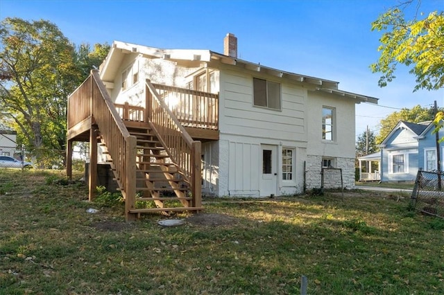 back of property with a wooden deck and a lawn