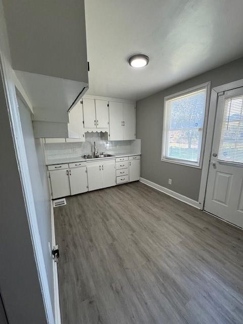 kitchen with decorative backsplash, light hardwood / wood-style floors, sink, and white cabinetry