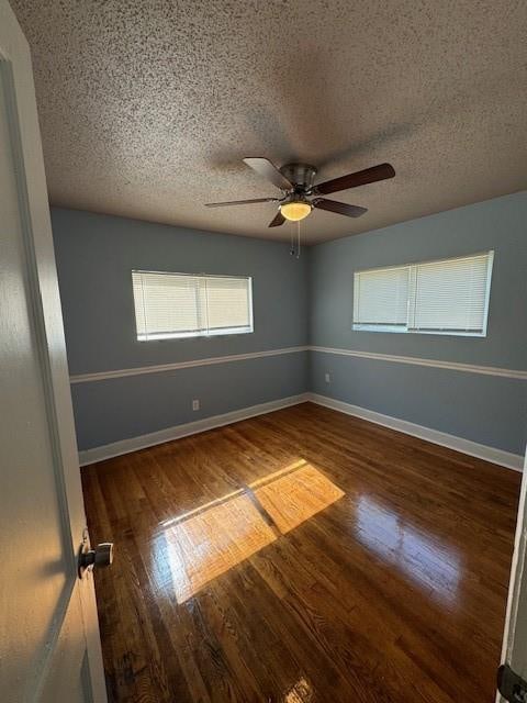 empty room featuring ceiling fan, dark wood-type flooring, and a textured ceiling