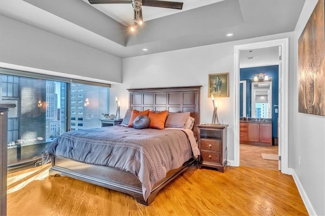 bedroom featuring ceiling fan, a raised ceiling, and light hardwood / wood-style flooring