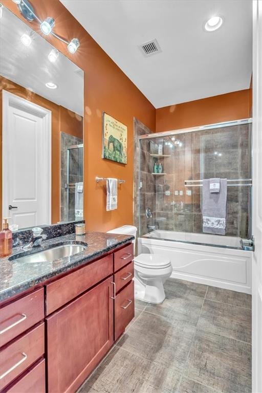 full bathroom with vanity, shower / bath combination with glass door, and toilet