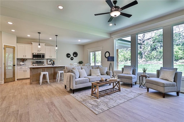 living room featuring ceiling fan, sink, and light hardwood / wood-style flooring